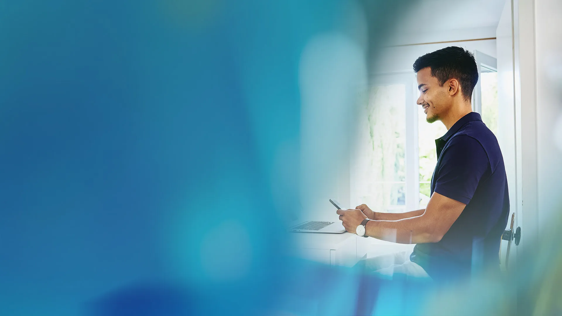 Young male technology professional smiling whilst working on his laptop