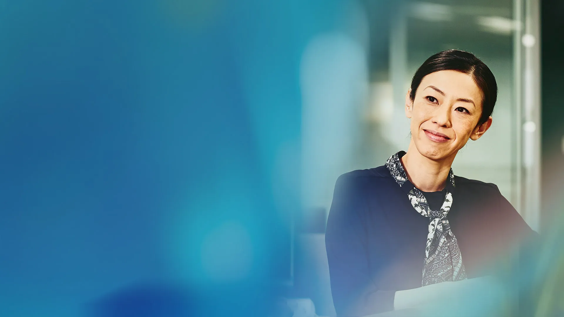 Professional woman smiling whilst sat working in a modern office